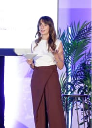 A female speaker on a stage presenting a talk